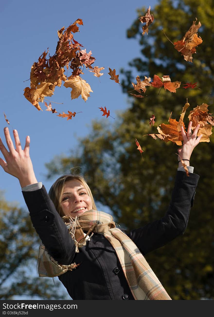 Young beautiful woman throwing the yellow leafs in the air. Young beautiful woman throwing the yellow leafs in the air