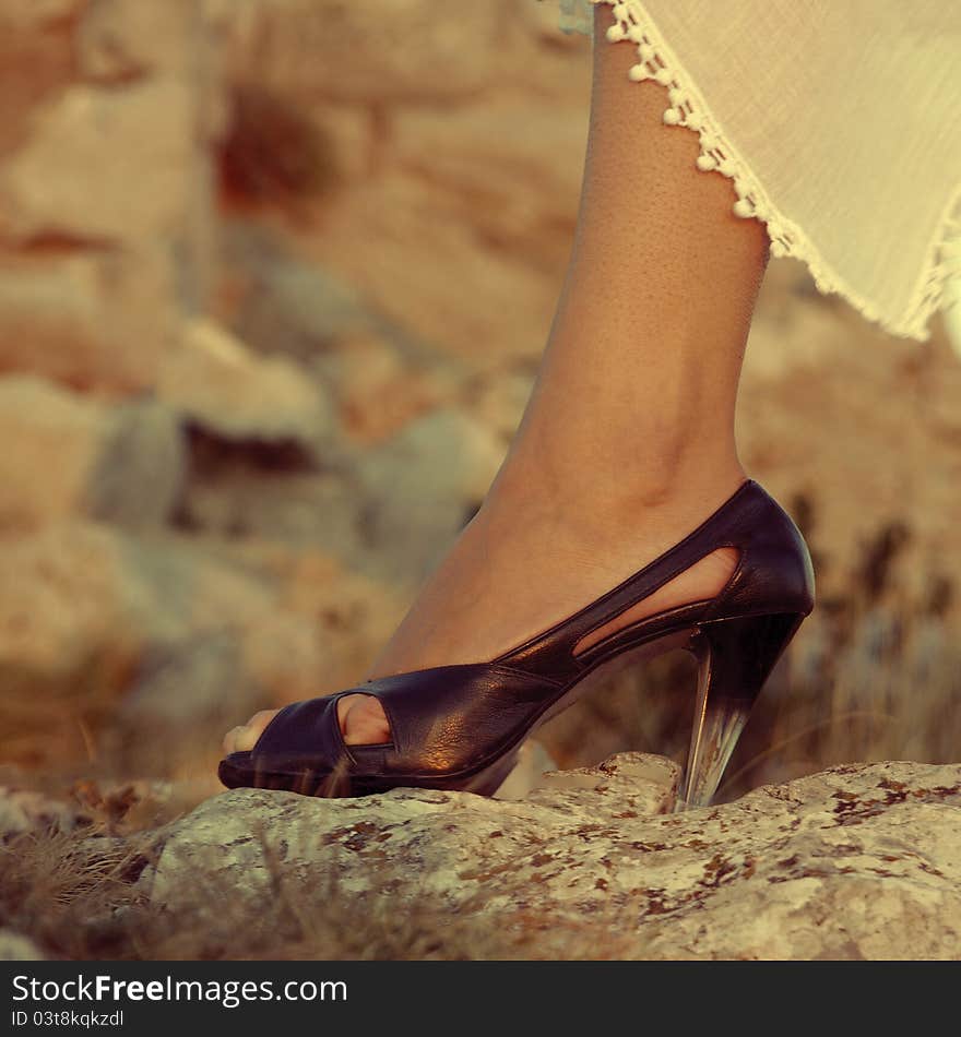 Female legs in high heels on the rock