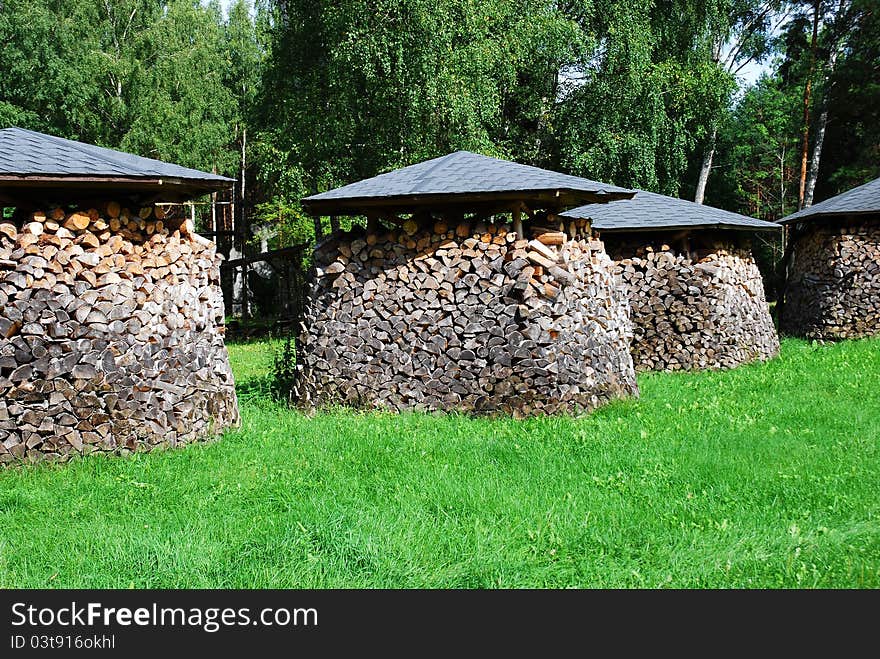 Piles of chopped wood on the green grass. Piles of chopped wood on the green grass.