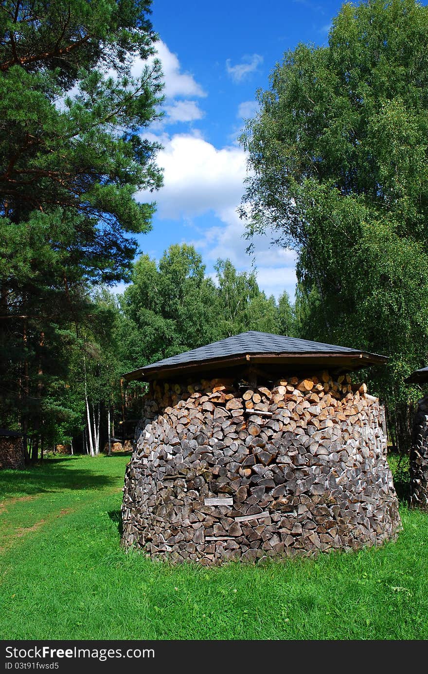 Pile of chopped firewood on the green grass with blue sky. Pile of chopped firewood on the green grass with blue sky