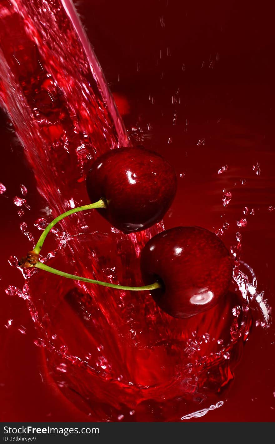 Cherry falling into the juice with huge splashes. Cherry falling into the juice with huge splashes