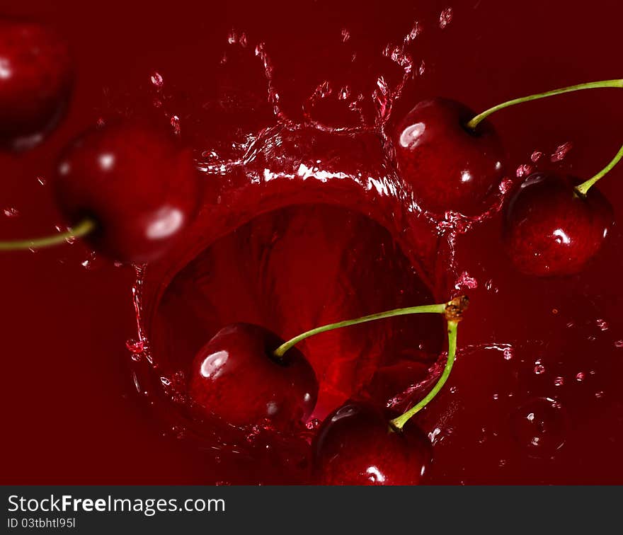 Cherry falling into the juice with huge splashes. Cherry falling into the juice with huge splashes