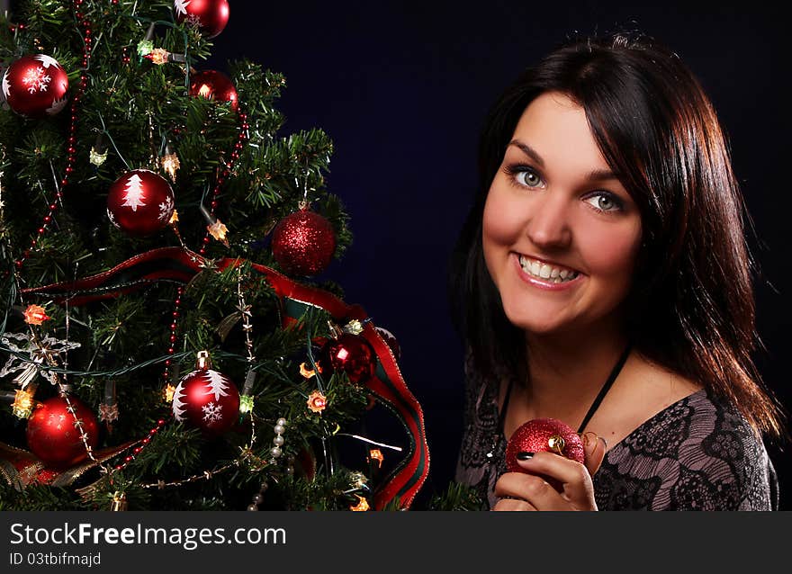 Happy woman are decorating the Christmas tree with different balls