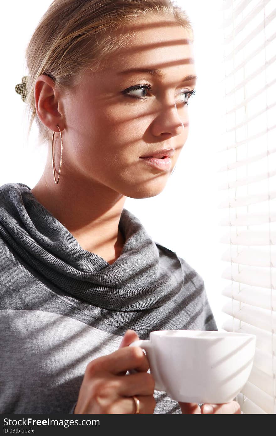 Beautiful woman with cup of coffee beside a window