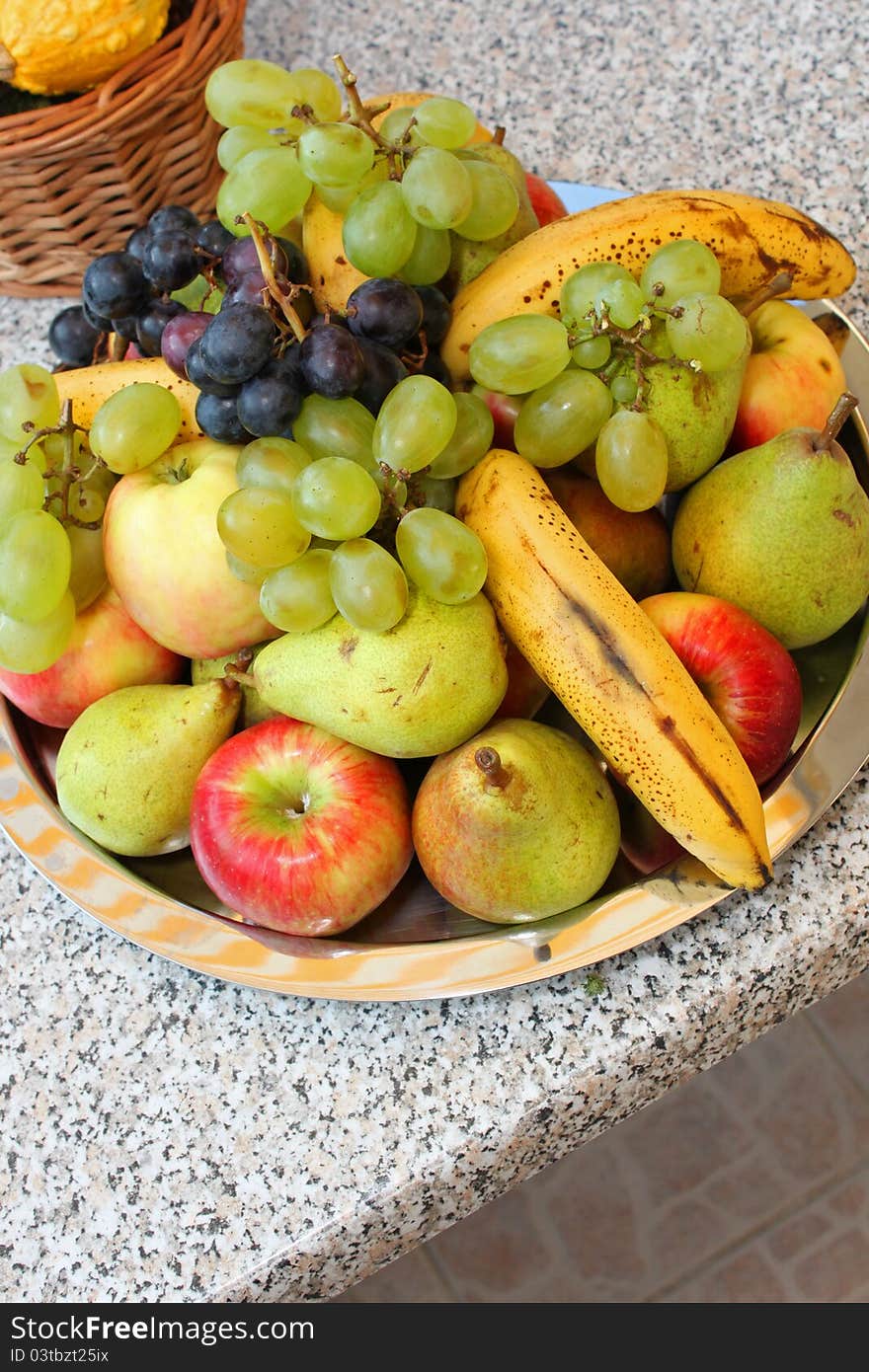 Assorted fruit plateau on grey outdoor table.