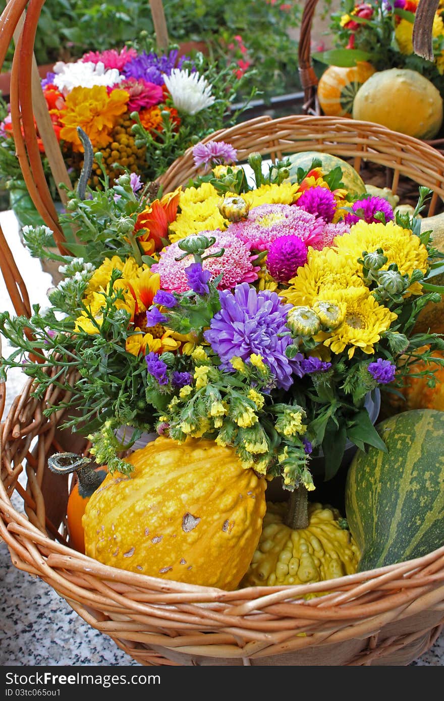 Assorted flower and pumpkin basket on outdoor grey table. Assorted flower and pumpkin basket on outdoor grey table.