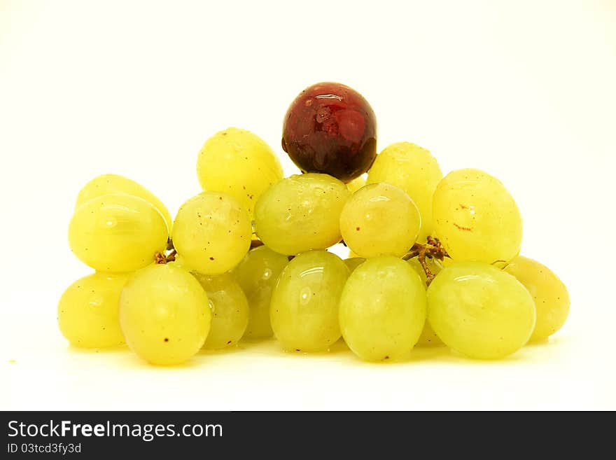 Image of a cluster of green grapes with a black grape.