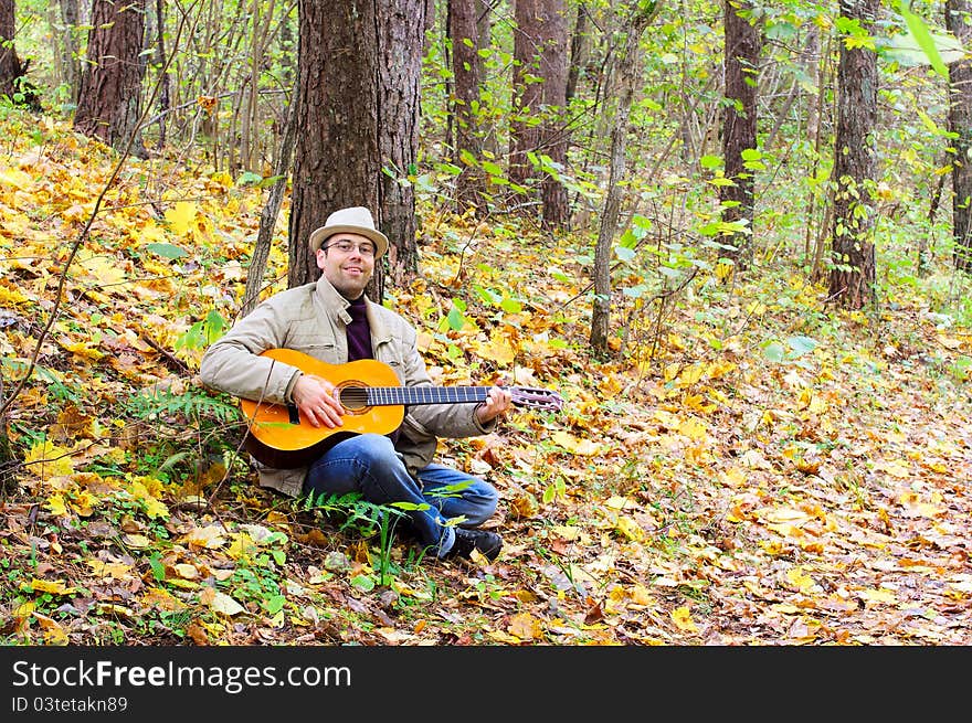 Man Is Playing A Guitar In Autumn Forest