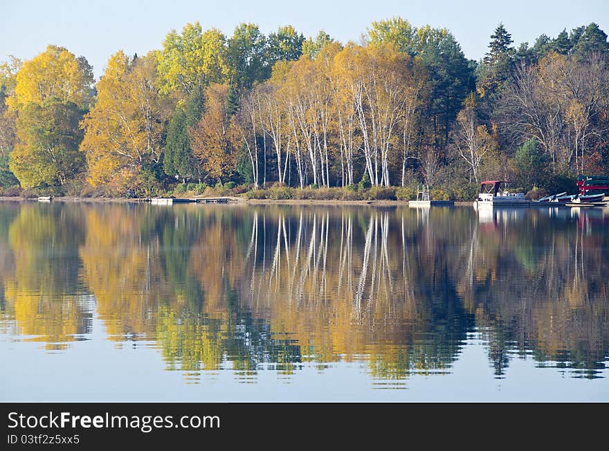 Fading colors in the tree reflected on a calm lake. Fading colors in the tree reflected on a calm lake.