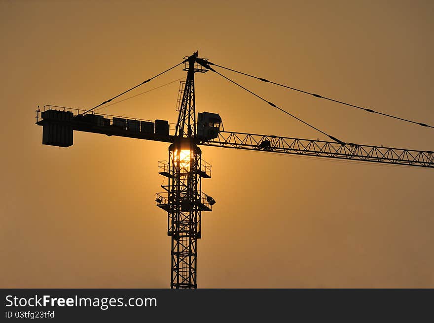 Three cranes at a construction site during sunset. Three cranes at a construction site during sunset.