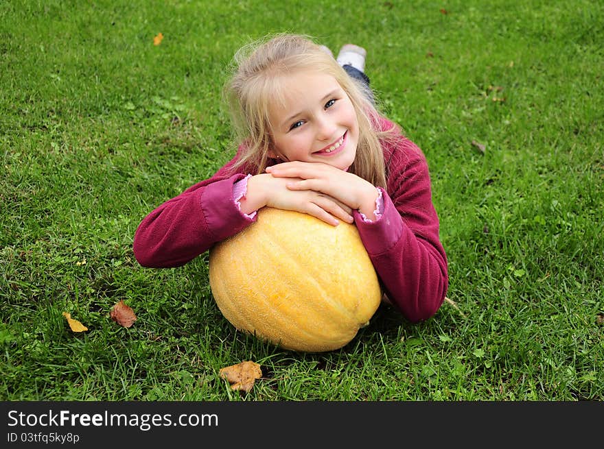 Little girl laying on green grass with pumpkin. Little girl laying on green grass with pumpkin