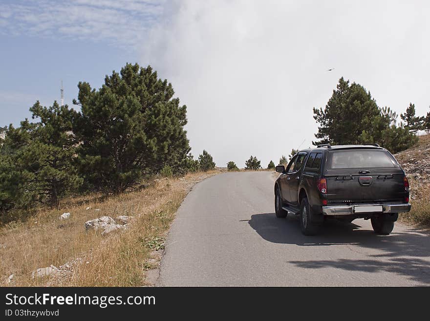 Black car moves along a mountain road up