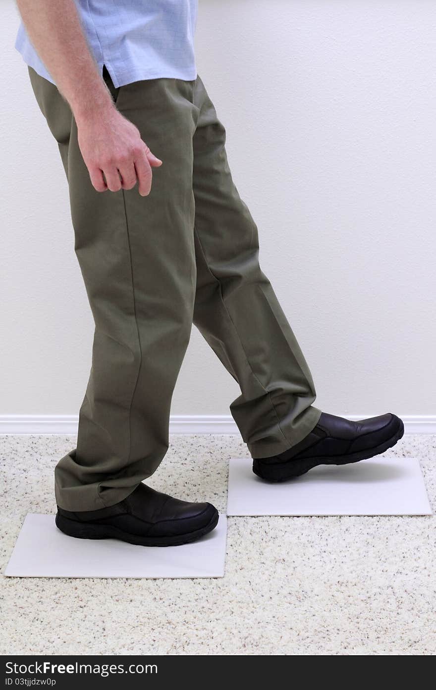 Lower body of relaxed man walking over two light gray empty paper boards. Lower body of relaxed man walking over two light gray empty paper boards.