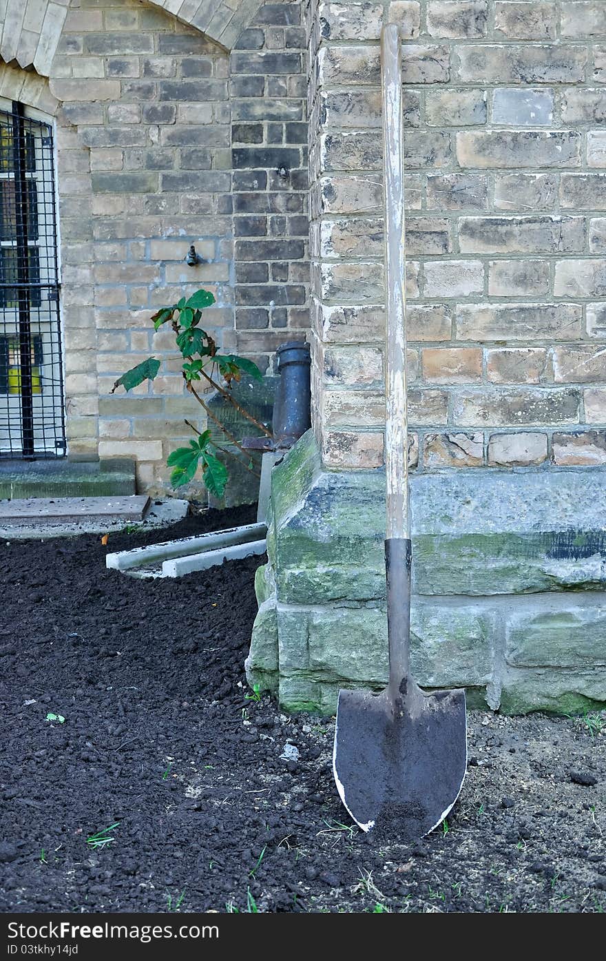 Spade leaning against stone wall in garden. Spade leaning against stone wall in garden