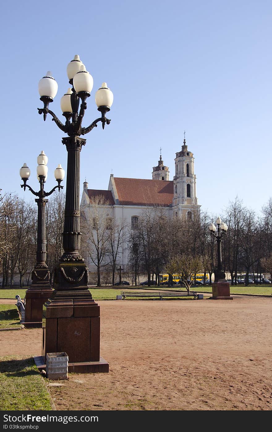 Antique lamps in Lukiskes Square in Vilnius, and the church in the distance. Antique lamps in Lukiskes Square in Vilnius, and the church in the distance.