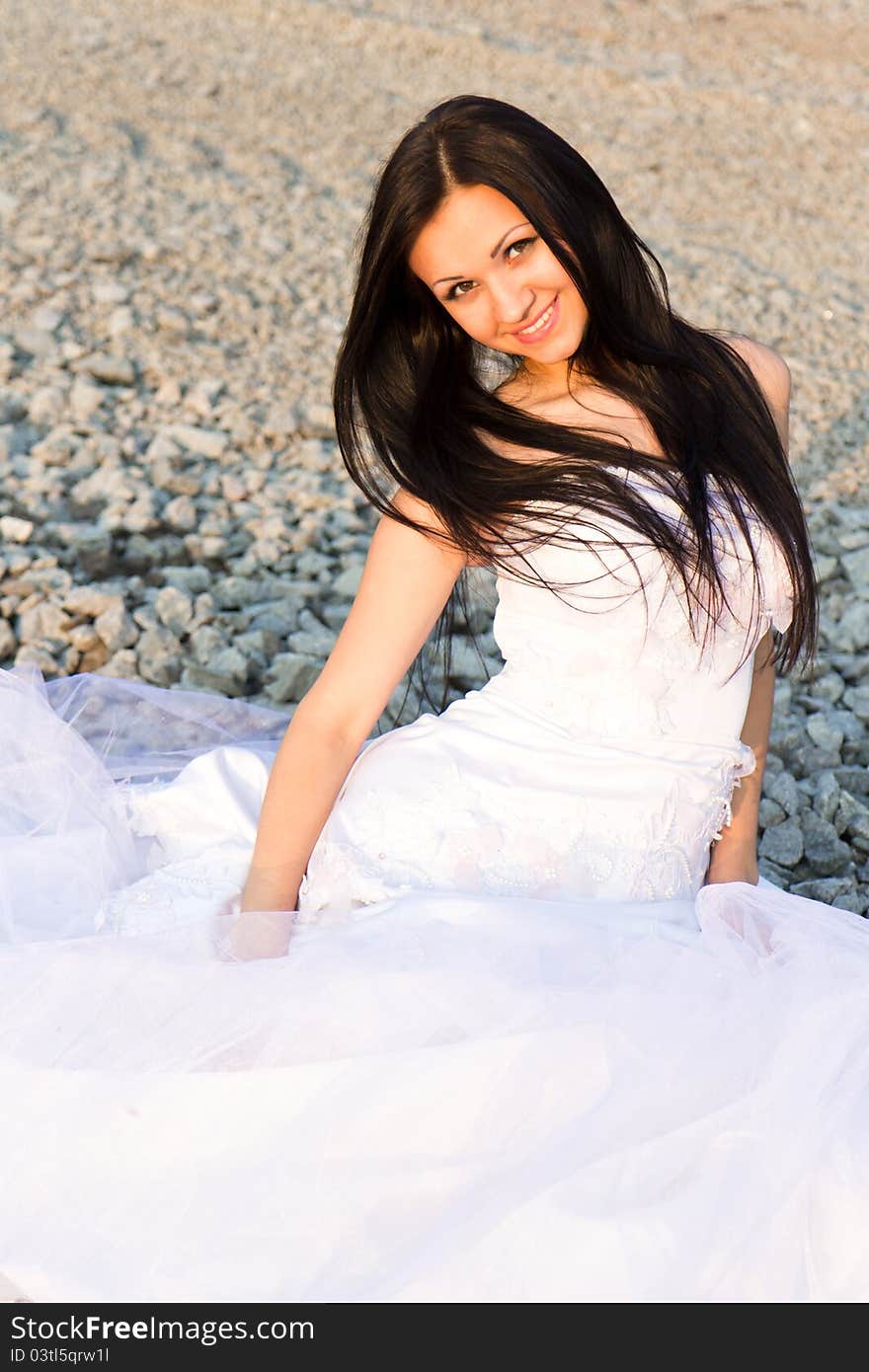 Portrait of a beautiful bride on pebbles outdoor