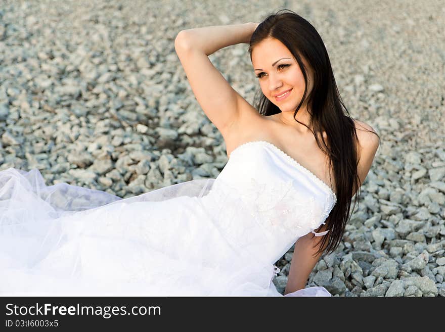 Portrait of a beautiful bride on pebbles outdoor