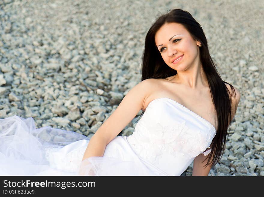 Portrait of a beautiful bride on pebbles outdoor