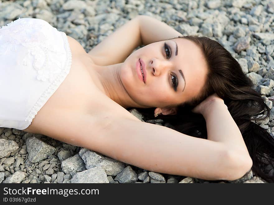 Portrait of a beautiful bride on pebbles outdoor