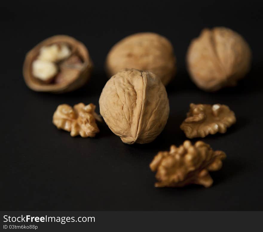 Cracked and whole walnuts in black background