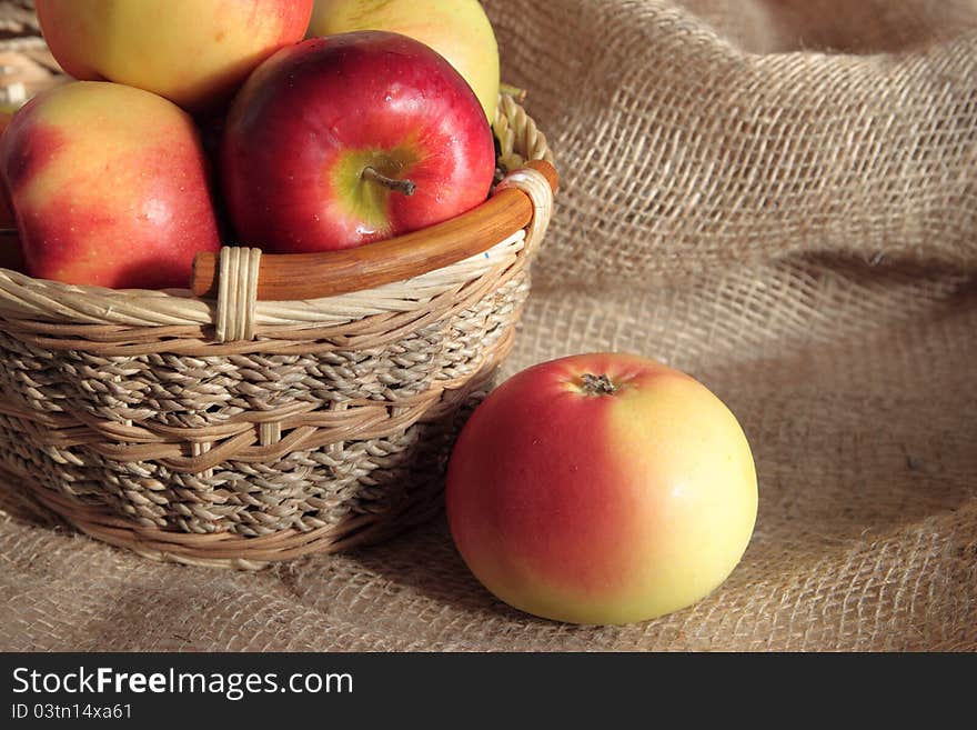 Apples in a basket and one apple lies nearby. Apples in a basket and one apple lies nearby.