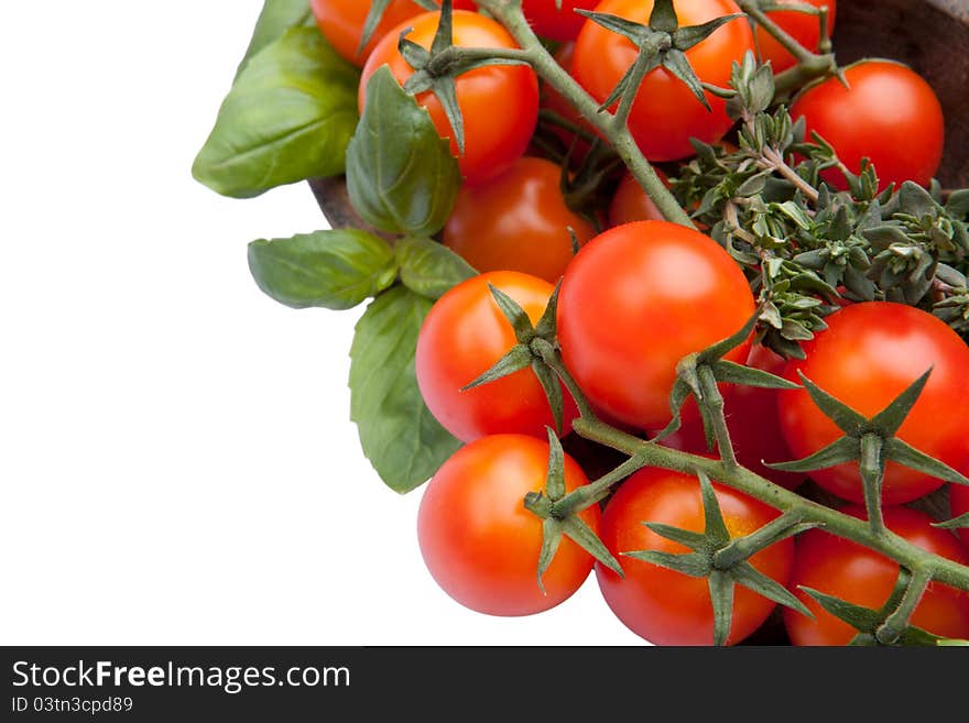 Cherry tomatoes with basil and thyme in wood plate isolated on white