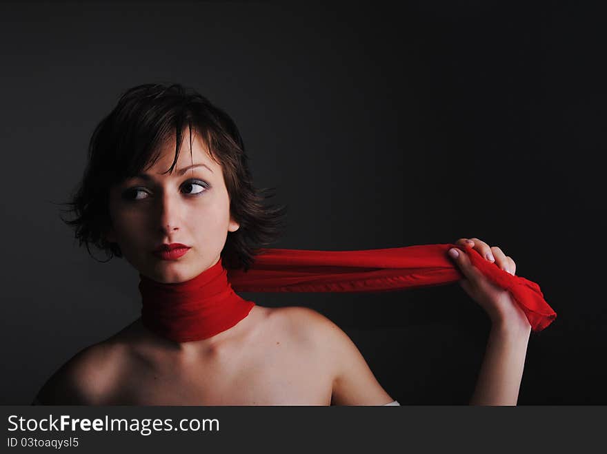 Portrait of girl in red a scarf on a grey background.