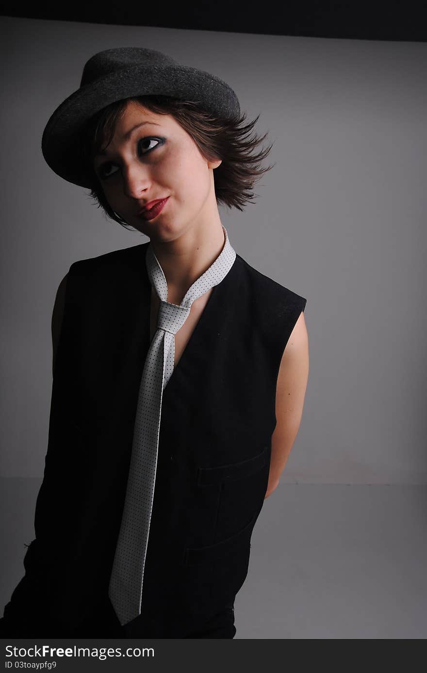 Girl in a tie and hat on near a brick wall. Girl in a tie and hat on near a brick wall.