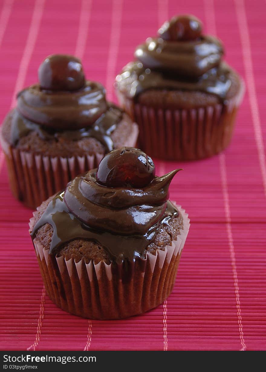 Delicious chocolate cup cakes with dark chocolate cream and cherries