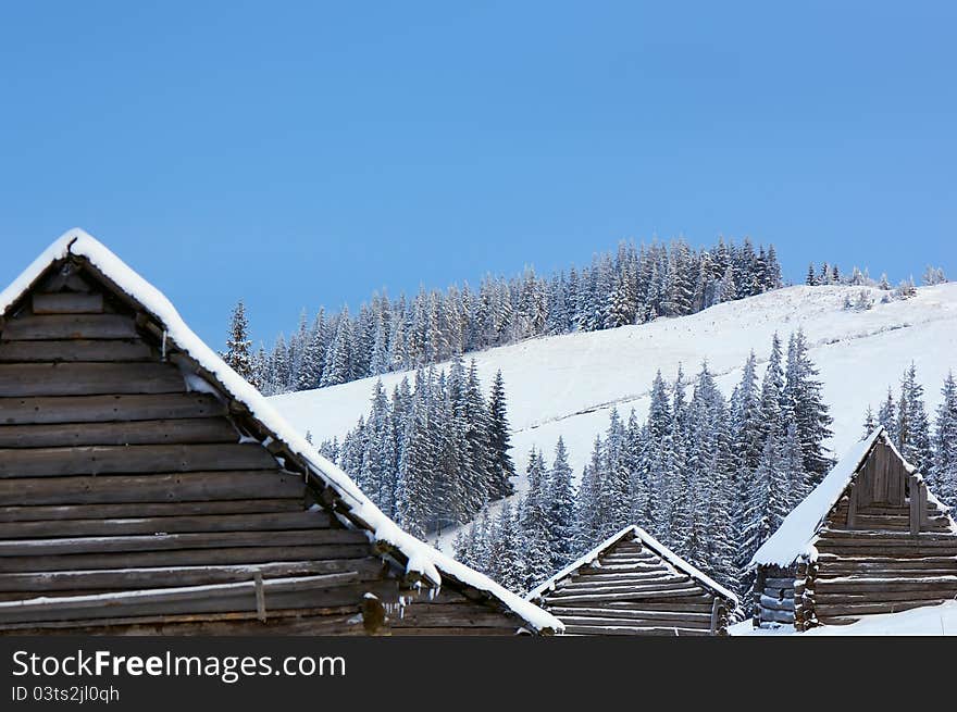 Winter background with roofs of houses and slopes of mountains. Ukraine, Carpathians