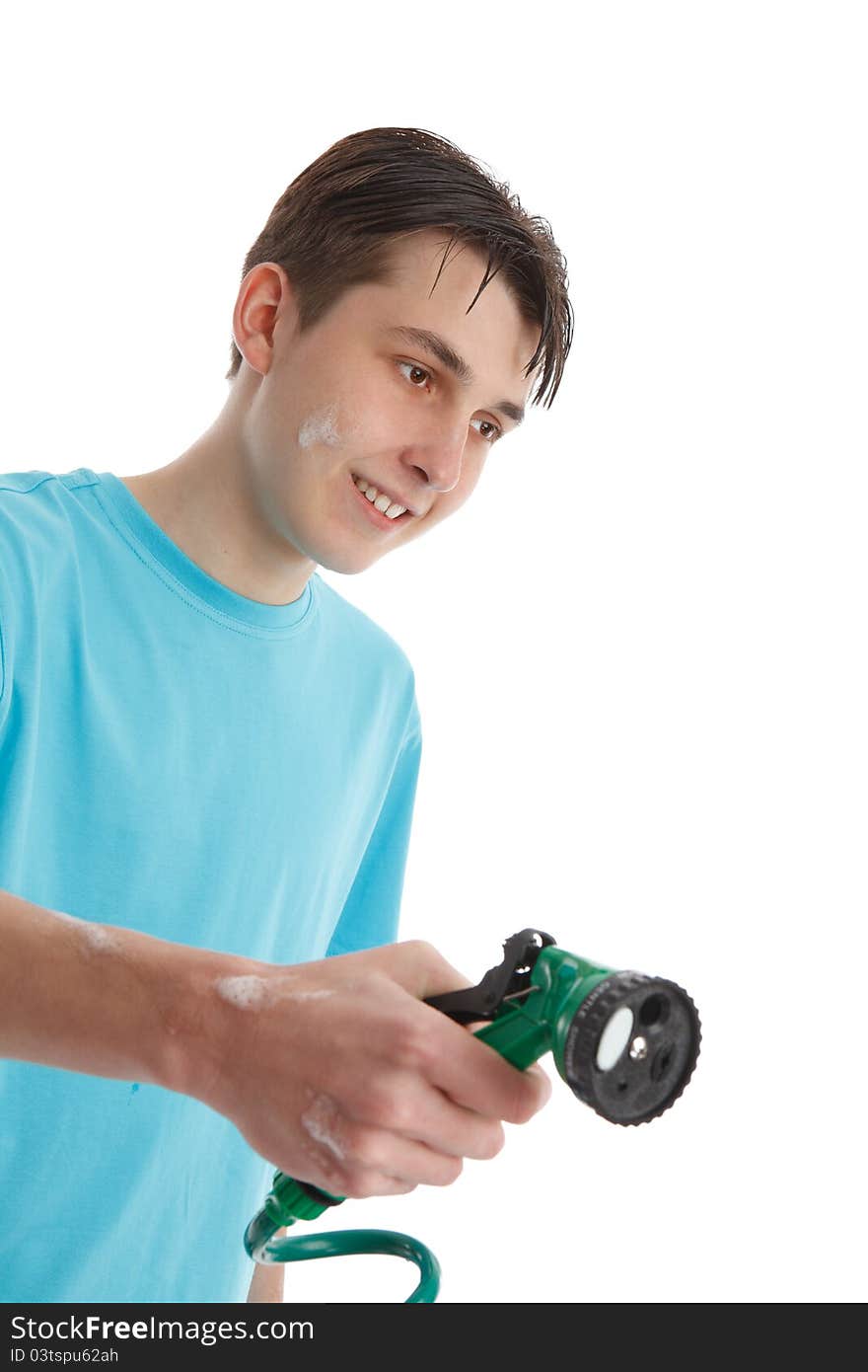 A teenage boy using a garden hose and trigger nozzle spray attachmant.