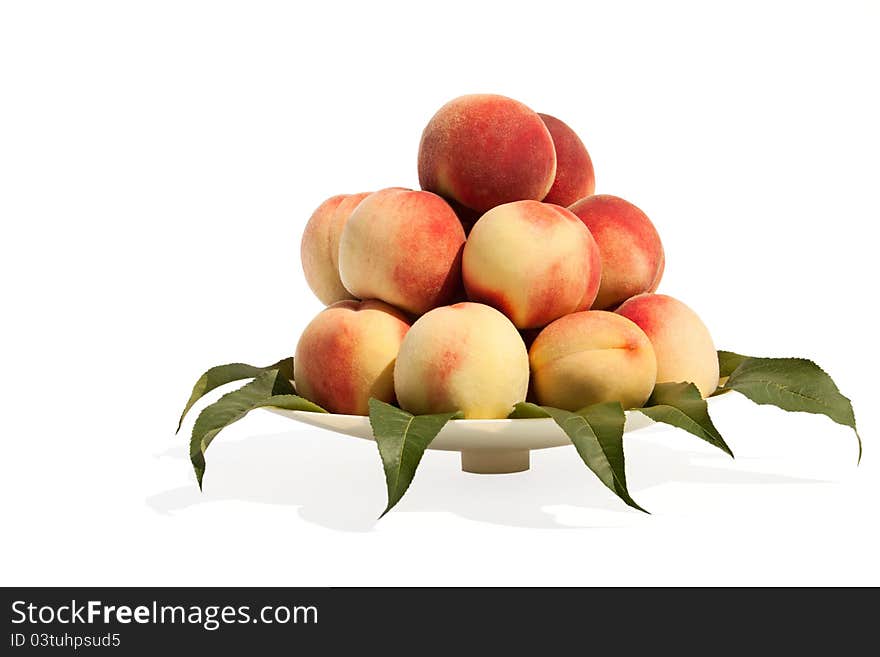 The pile from peaches in the plate against the white background. The pile from peaches in the plate against the white background