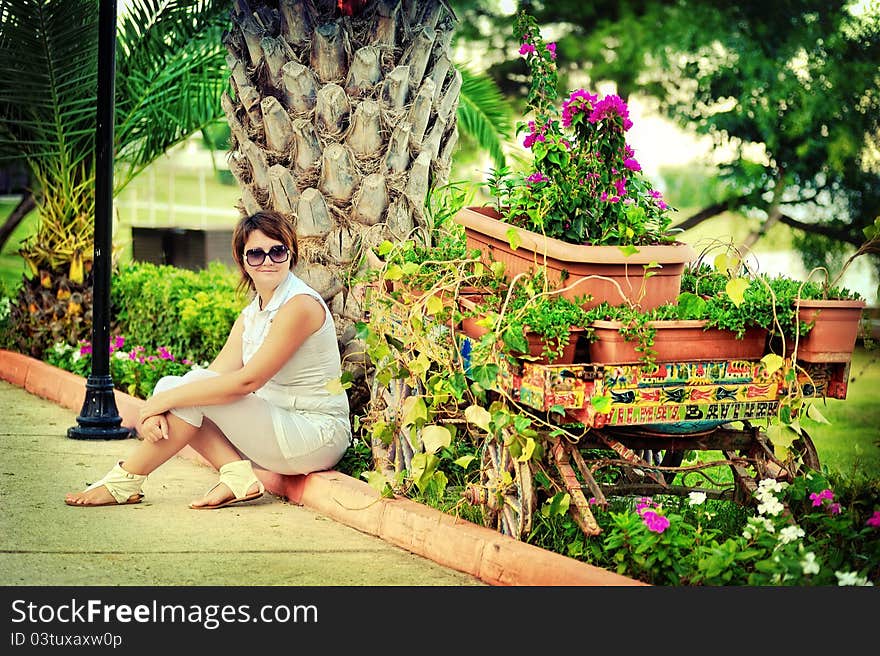 The girl in park in the summer on avenue between bushes of greens wearing spectacles