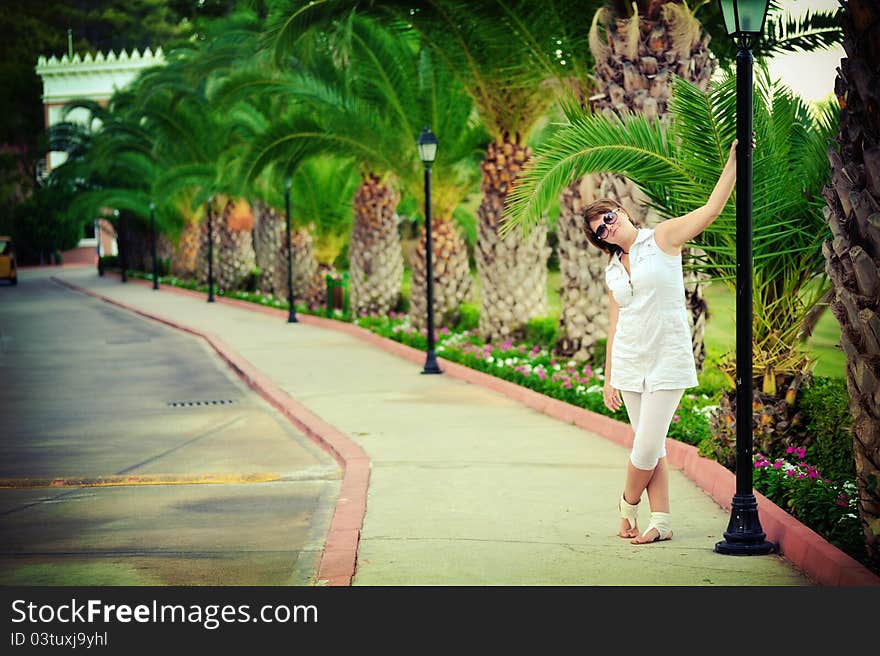 The girl in park in the summer on avenue between bushes of greens wearing spectacles