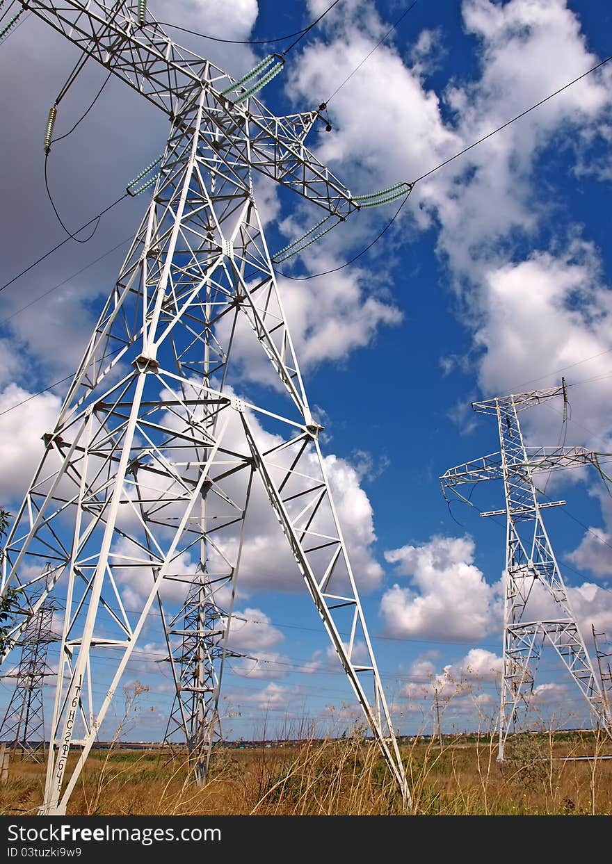 Masts of electric mains and cloudy sky