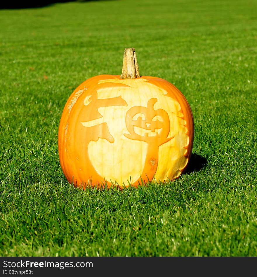 Picture of a pumpkin, with silhouette of a witch and a pumpkin cut in the surface. Standing on a lawn. Picture of a pumpkin, with silhouette of a witch and a pumpkin cut in the surface. Standing on a lawn