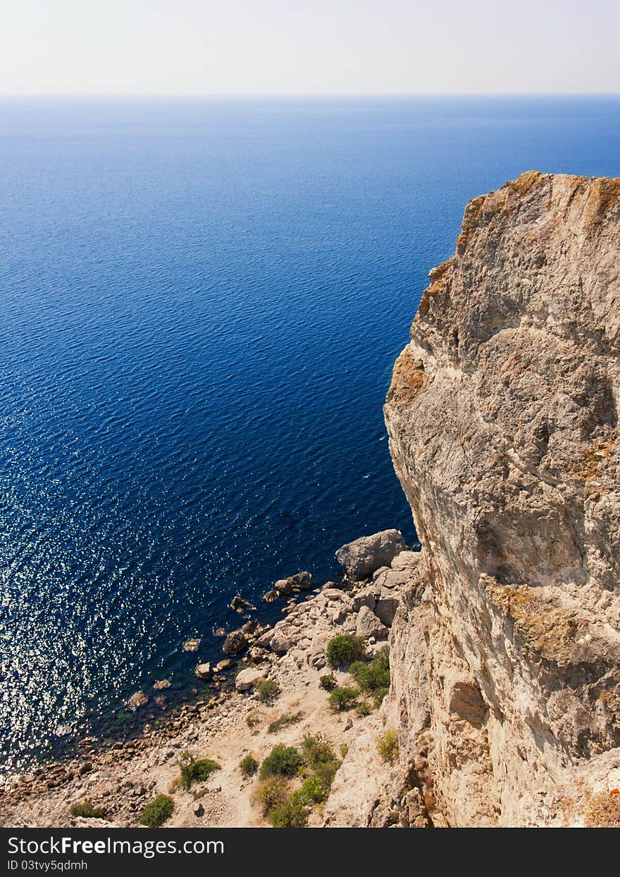 Travel, vacation background - vertical rock, mountain, deep blue sea and beautiful sky. Travel, vacation background - vertical rock, mountain, deep blue sea and beautiful sky