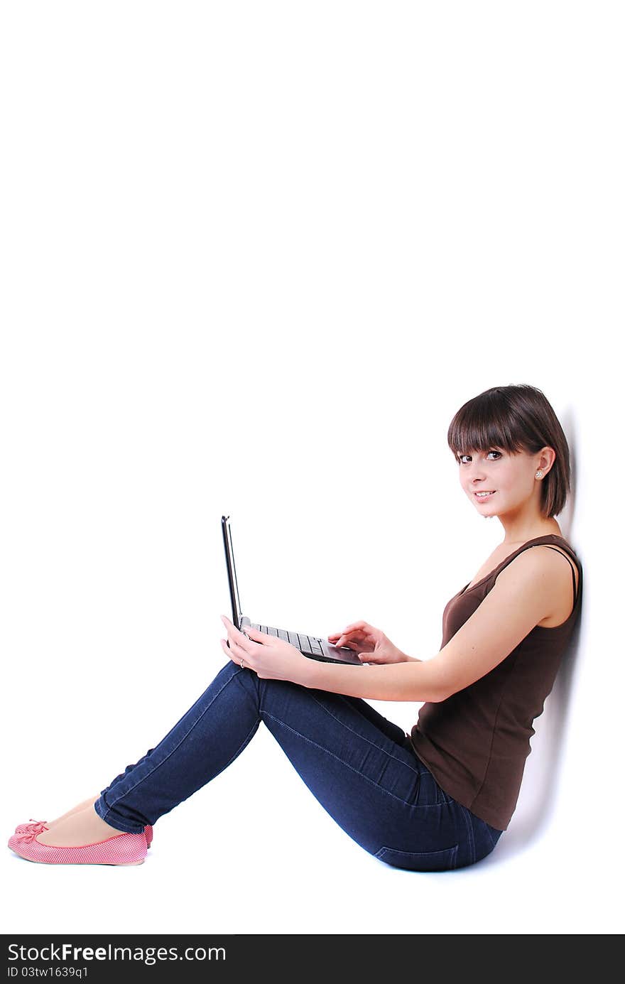 Pretty woman sitting against wall with laptop