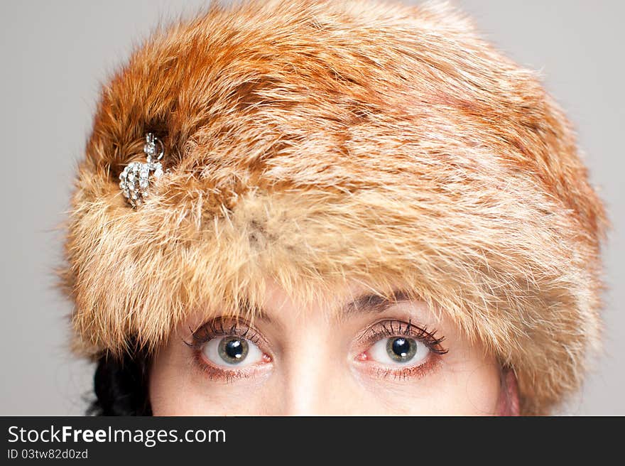 Mature brunette in d fox hat on gray background. Intents look. Mature brunette in d fox hat on gray background. Intents look