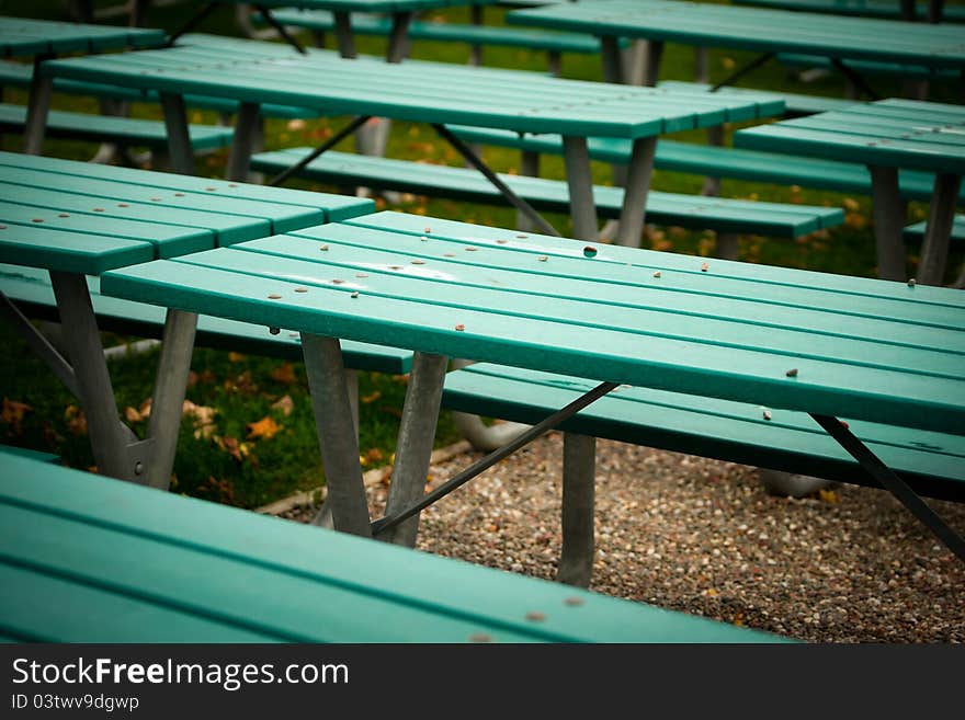 Close-up of many green, steel-structured picnic tables grouped tightly together. Close-up of many green, steel-structured picnic tables grouped tightly together.