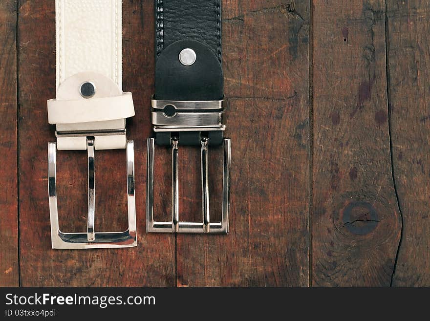 White and black leather belts hanging on old wooden background. White and black leather belts hanging on old wooden background