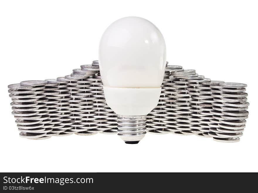 Power saving energy lightbulb with stacked silver coins behind over white background. Power saving energy lightbulb with stacked silver coins behind over white background.