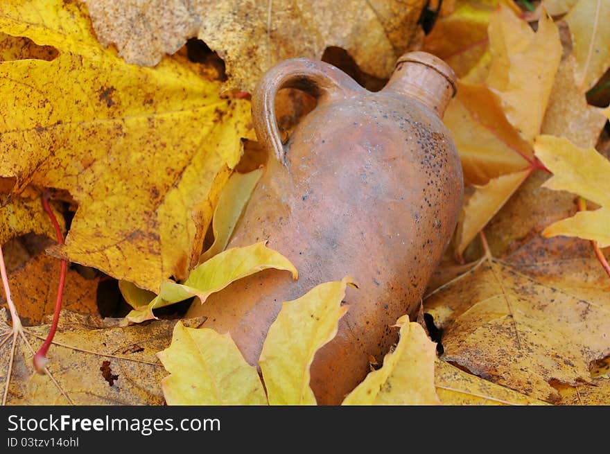 Vintage ceramic bottle in the middle of the fallen maple leaves. Vintage ceramic bottle in the middle of the fallen maple leaves