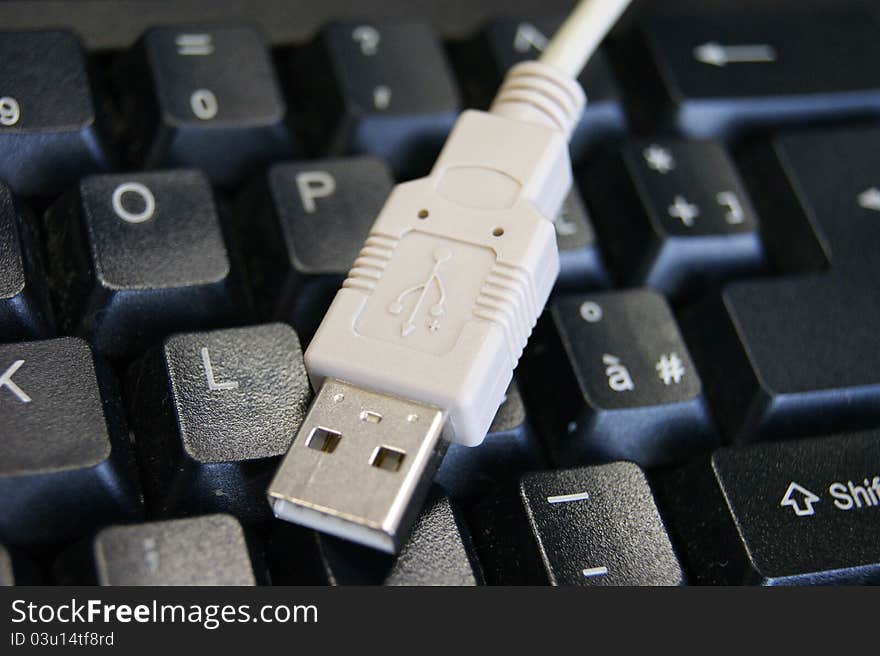 White USB cable on a black keyboard. White USB cable on a black keyboard