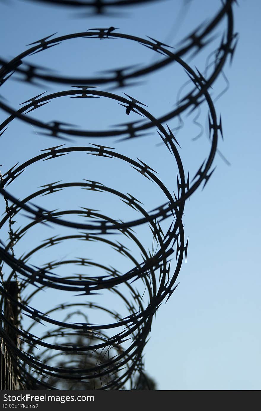 Spiralling barbed ribbon silhouetted against a blue sky.