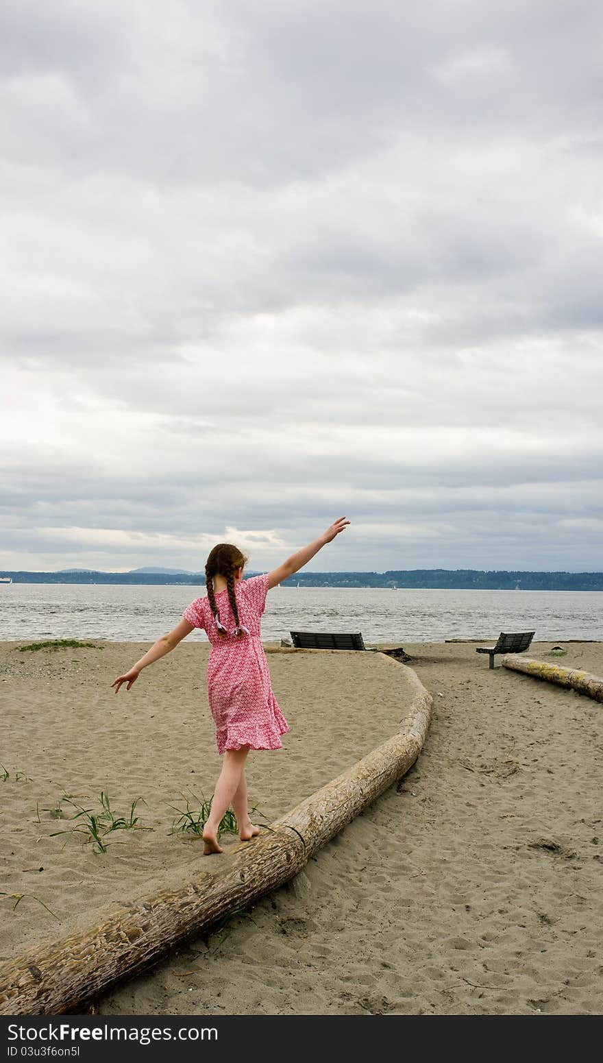 Young Girl Balancing On Log At Beach