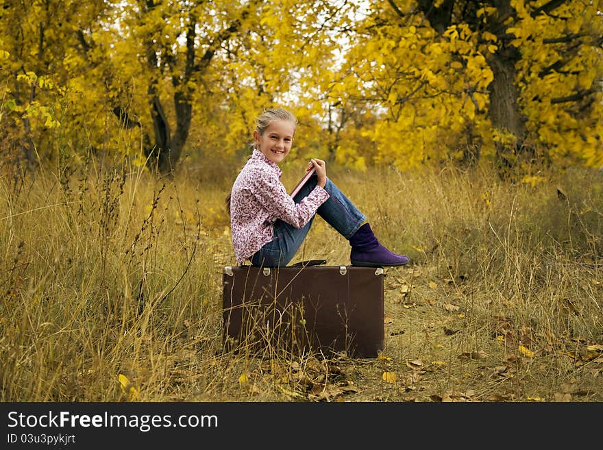 Little Girl Is Reading A Book In Autumn