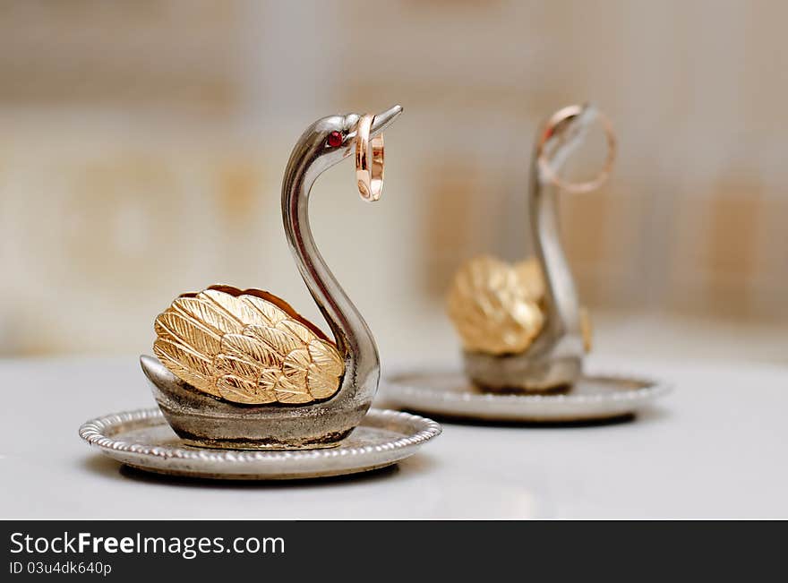 Two gold wedding rings on beautiful swans