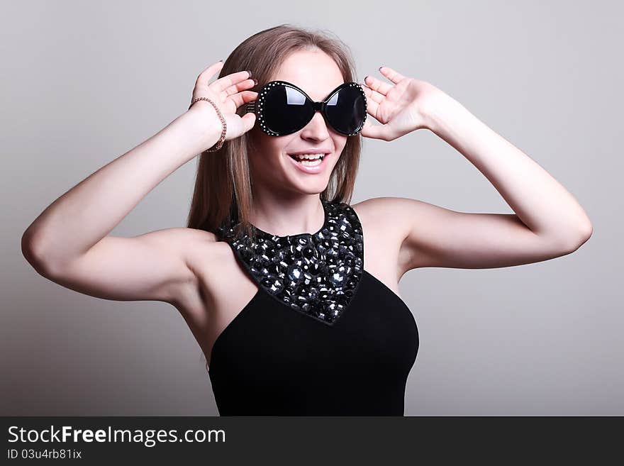 Fashion woman in a stylish glasses on gray background