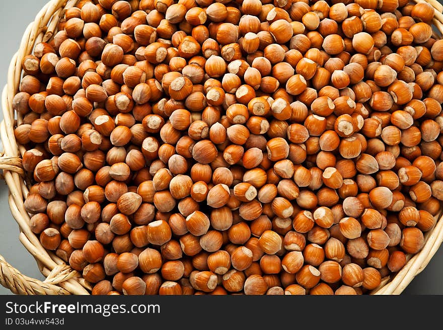 Hazelnuts in a basket on gray background